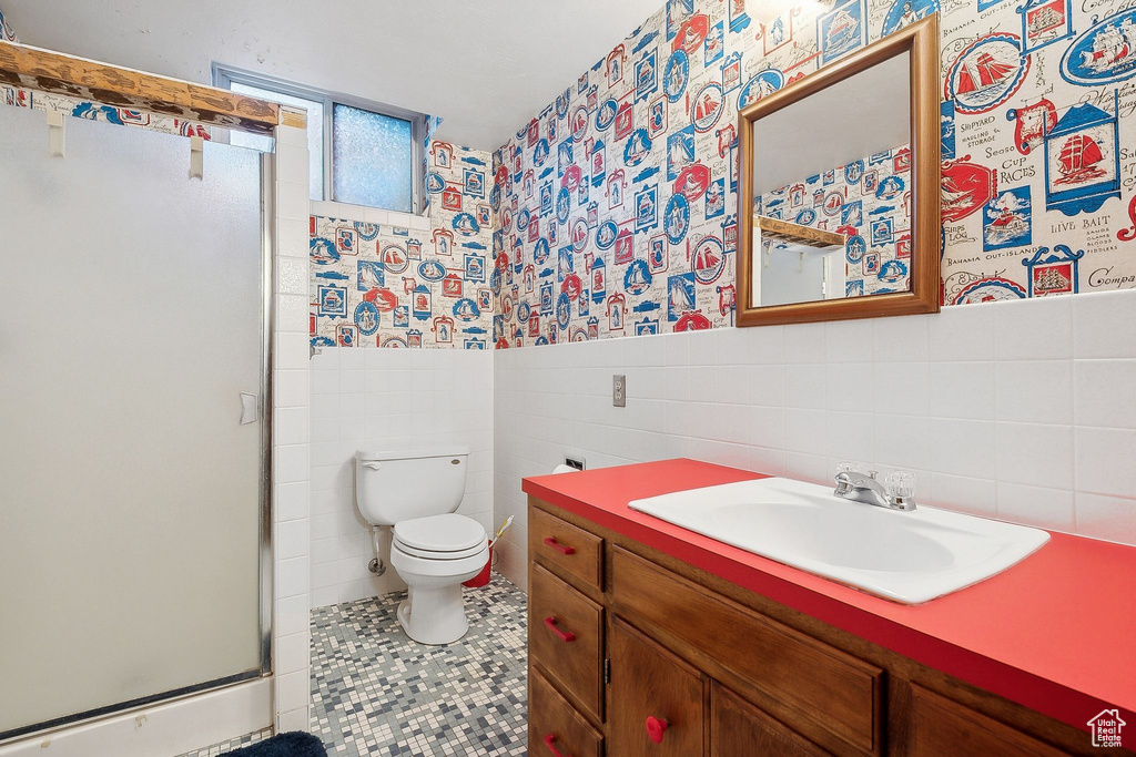 Full bath with tile walls, wallpapered walls, a stall shower, toilet, and a wainscoted wall