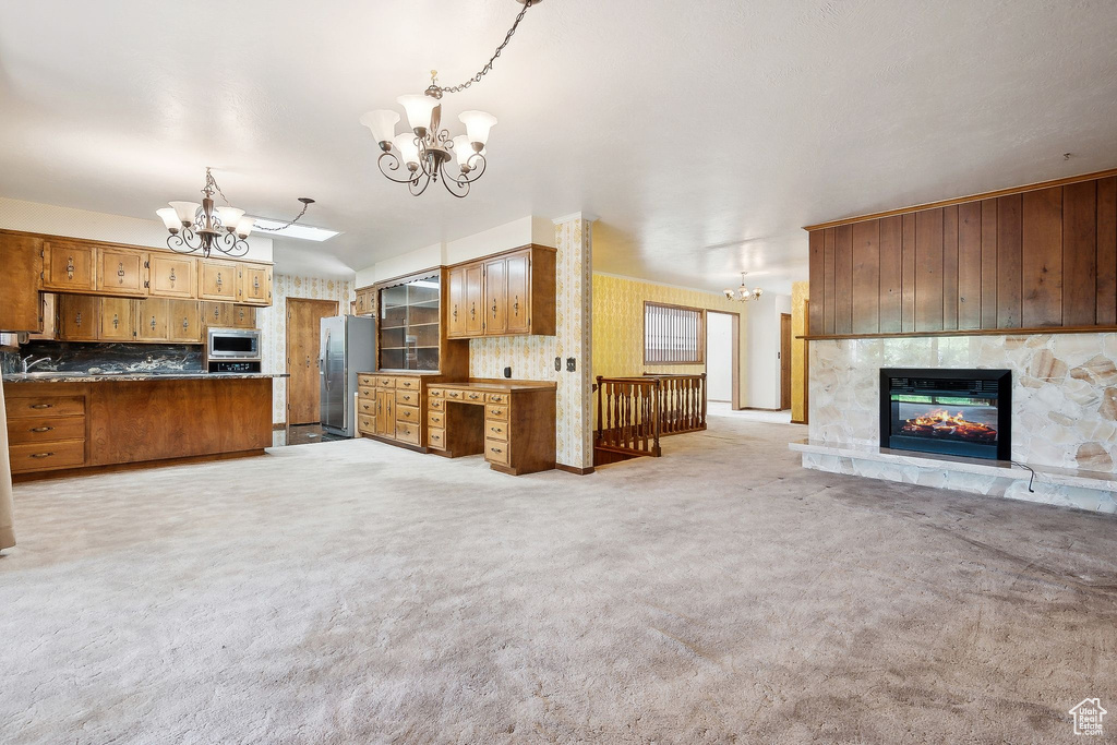Kitchen featuring a chandelier, open floor plan, stainless steel appliances, and brown cabinetry