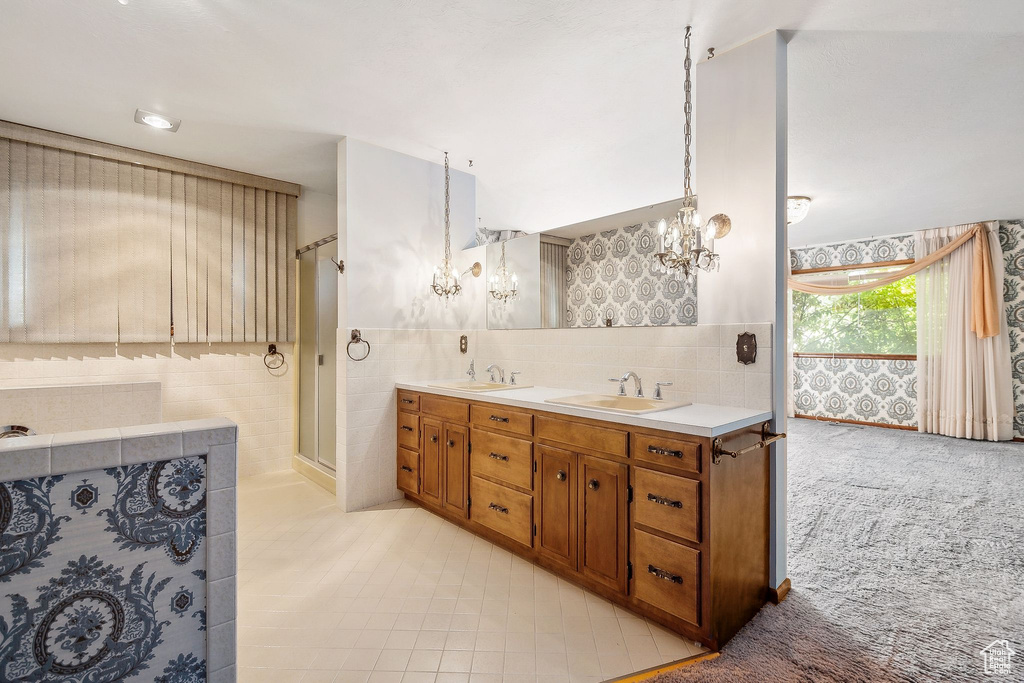 Full bath with a chandelier, tile walls, double vanity, a stall shower, and tile patterned floors
