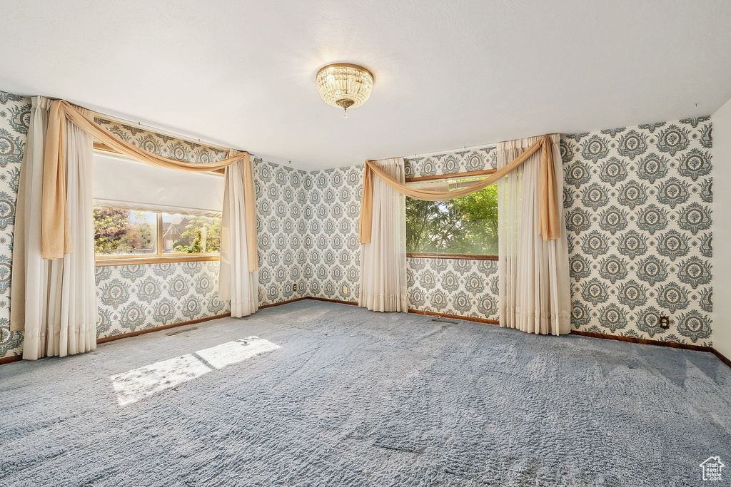 Carpeted spare room with wallpapered walls, healthy amount of natural light, and baseboards