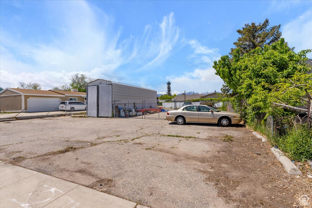 View of parking / parking lot featuring fence and a storage unit