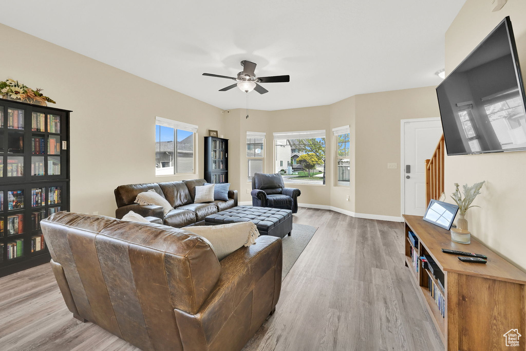 Living room with light wood-type flooring, a ceiling fan, and baseboards