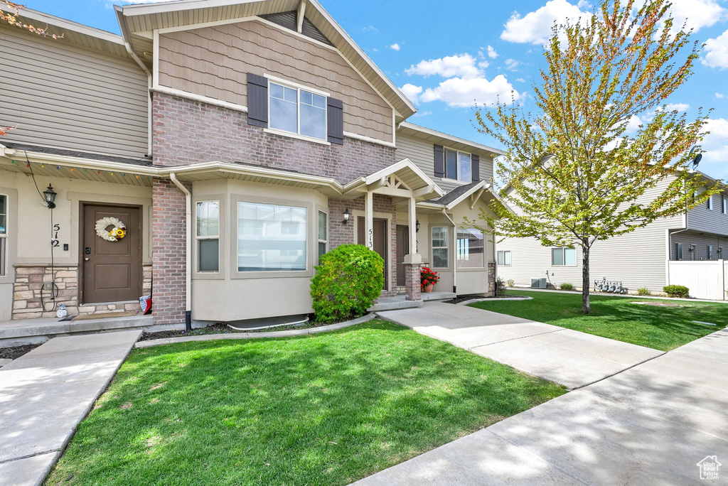 Townhome / multi-family property with brick siding and a front yard