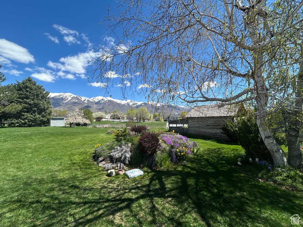 View of green lawn featuring a mountain view and an outdoor structure