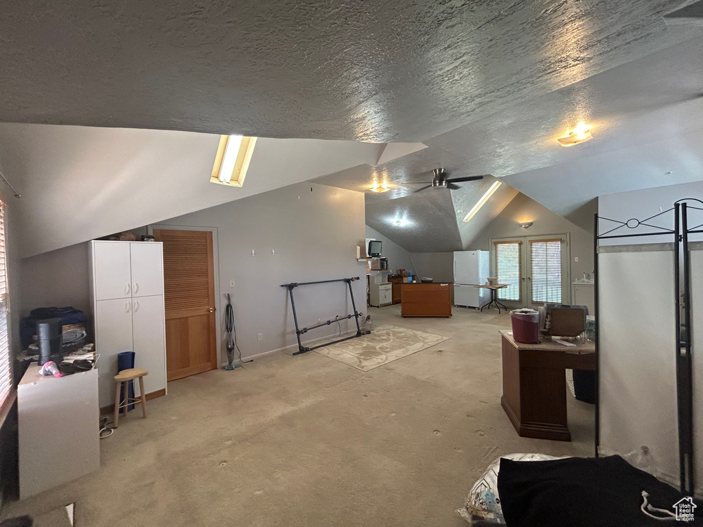 Additional living space with vaulted ceiling, ceiling fan, light carpet, a textured ceiling, and baseboards