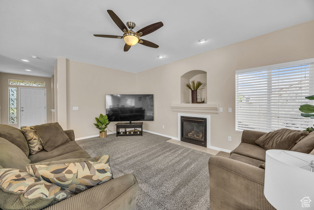 Carpeted living area featuring baseboards, ceiling fan, a fireplace with flush hearth, and recessed lighting