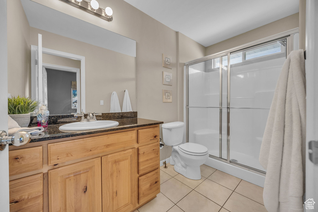 Bathroom featuring tile patterned flooring, a stall shower, toilet, and vanity