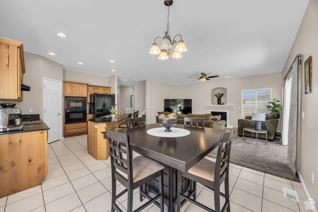 Dining room featuring light tile patterned floors, a ceiling fan, a fireplace, a chandelier, and recessed lighting
