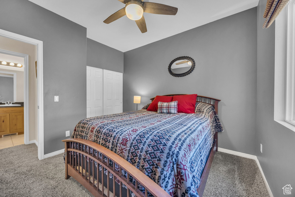 Carpeted bedroom with baseboards, a sink, a ceiling fan, and a closet