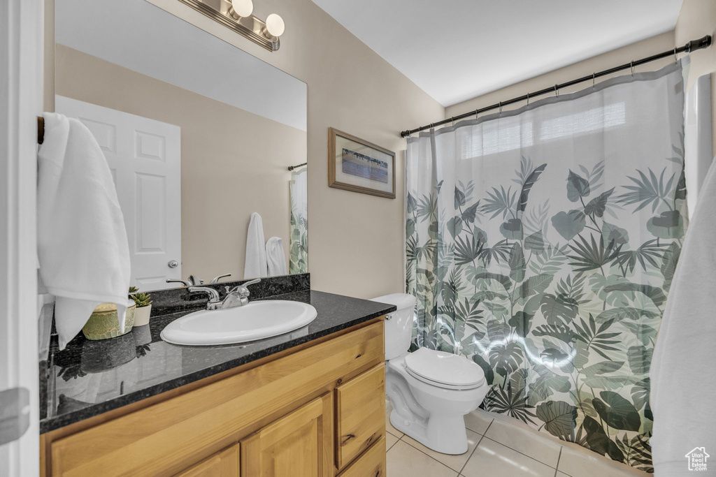 Full bathroom with tile patterned floors, toilet, vanity, and a shower with curtain