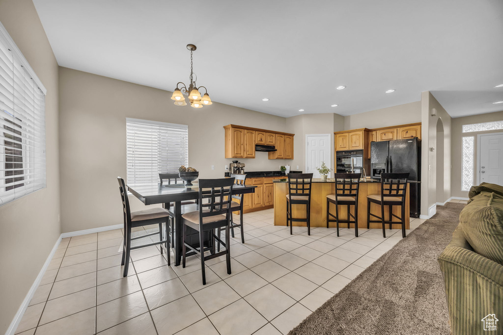 Dining space featuring a chandelier, baseboards, light tile patterned floors, recessed lighting, and arched walkways