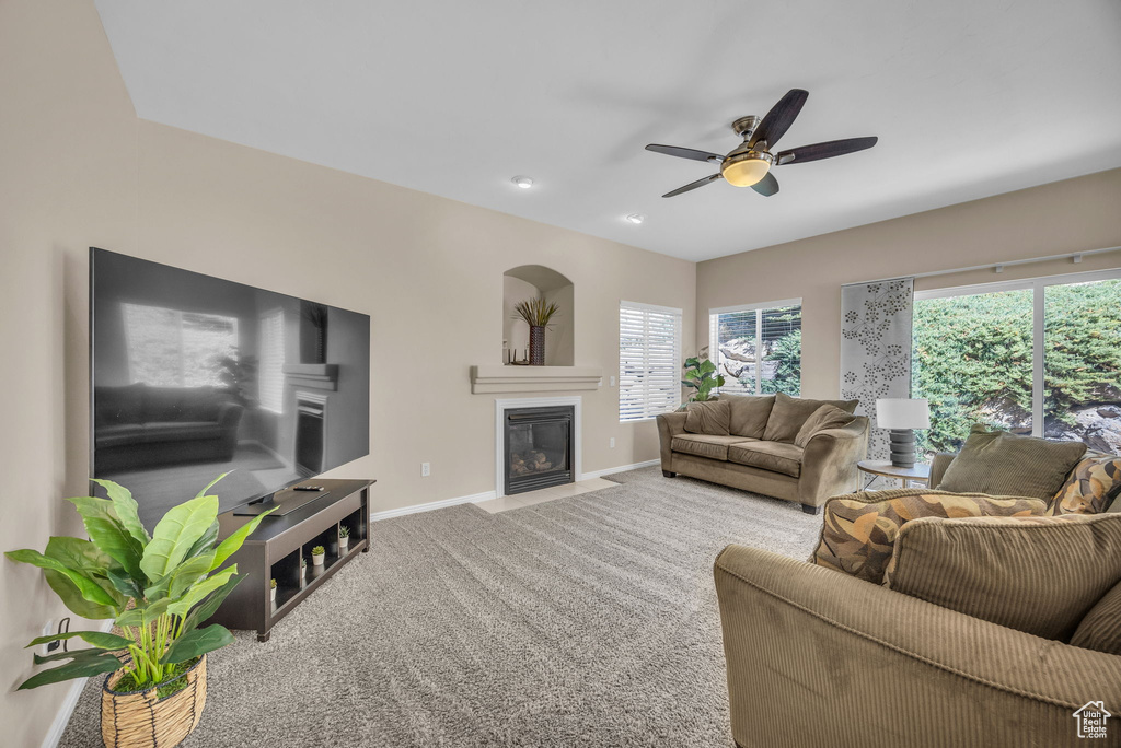 Living room featuring baseboards, plenty of natural light, carpet, and a fireplace with flush hearth