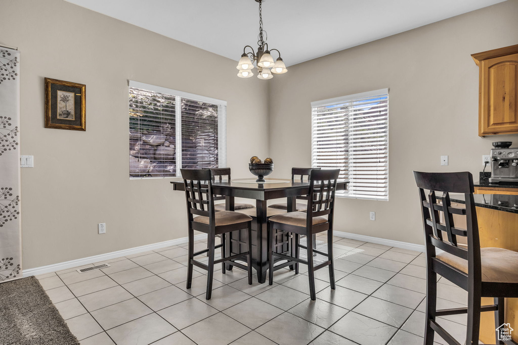 Dining area with a chandelier, light tile patterned floors, and baseboards