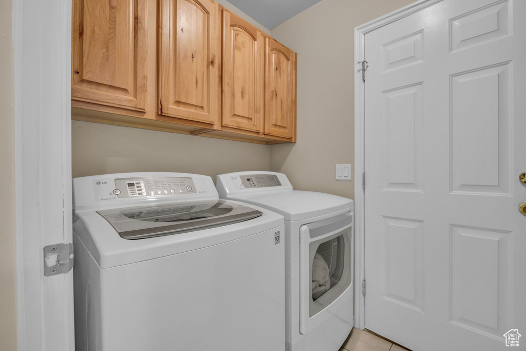 Laundry area featuring separate washer and dryer, cabinet space, and light tile patterned floors