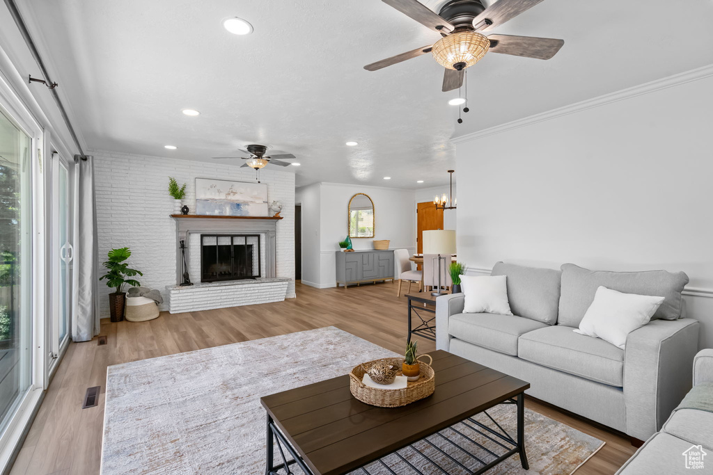 Living room with a ceiling fan, light wood-style floors, recessed lighting, ornamental molding, and a fireplace