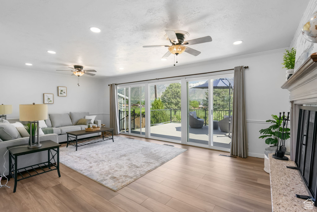 Living room featuring a ceiling fan, plenty of natural light, recessed lighting, wood finished floors, and crown molding