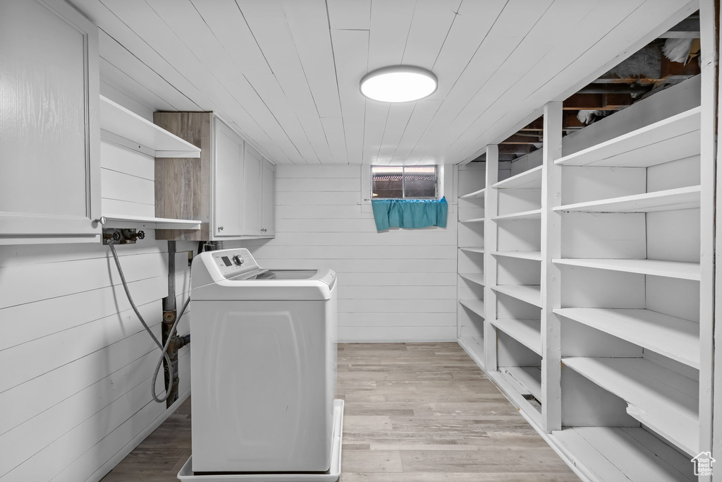Washroom with washing machine and clothes dryer, light wood-style flooring, wooden walls, and wood ceiling