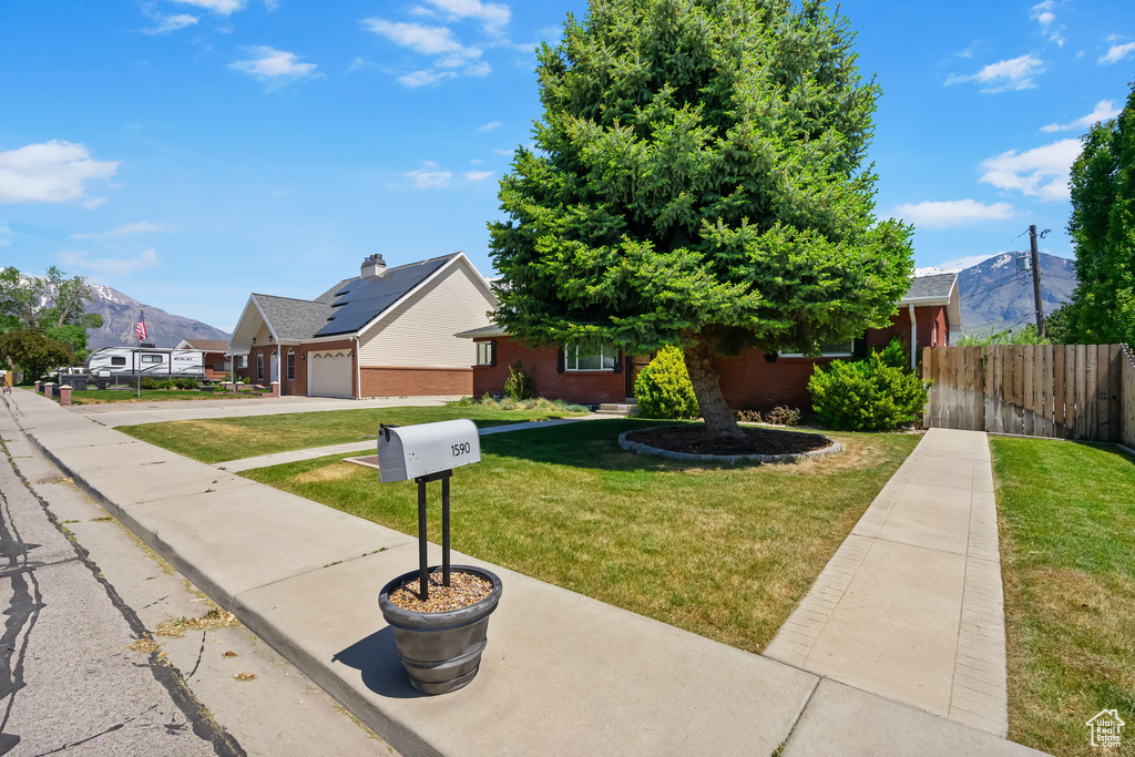 Obstructed view of property with a mountain view, an attached garage, driveway, and brick siding