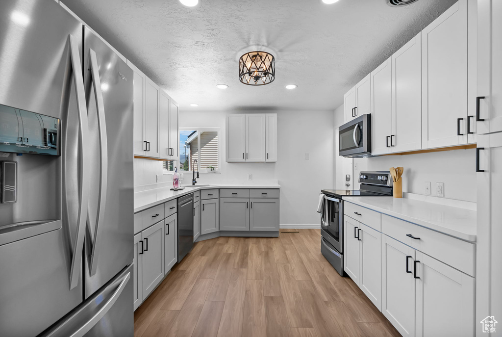 Kitchen with stainless steel appliances, light wood-style flooring, light countertops, recessed lighting, and gray cabinets