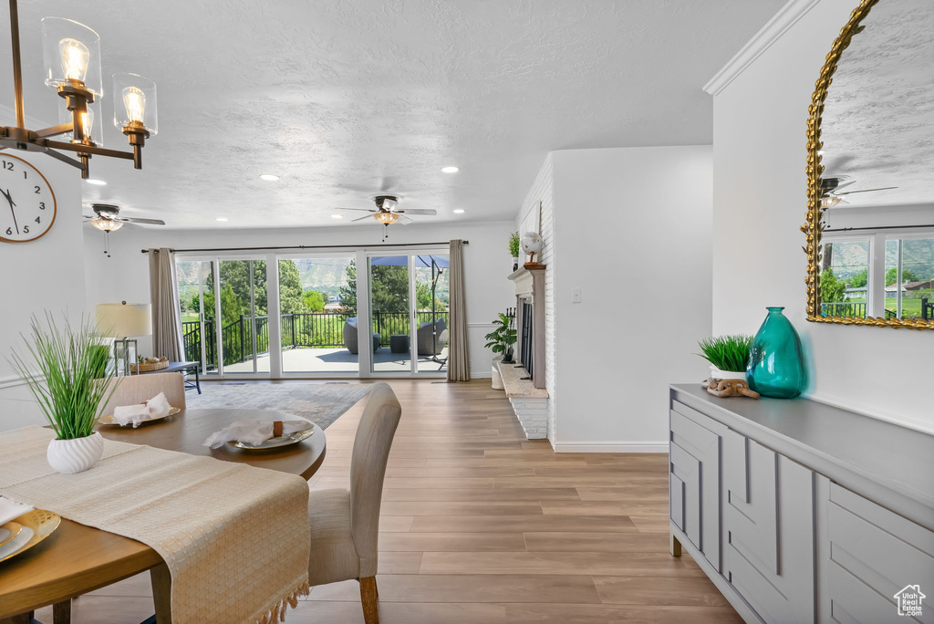 Dining space featuring a ceiling fan, healthy amount of natural light, light wood-type flooring, recessed lighting, and a textured ceiling