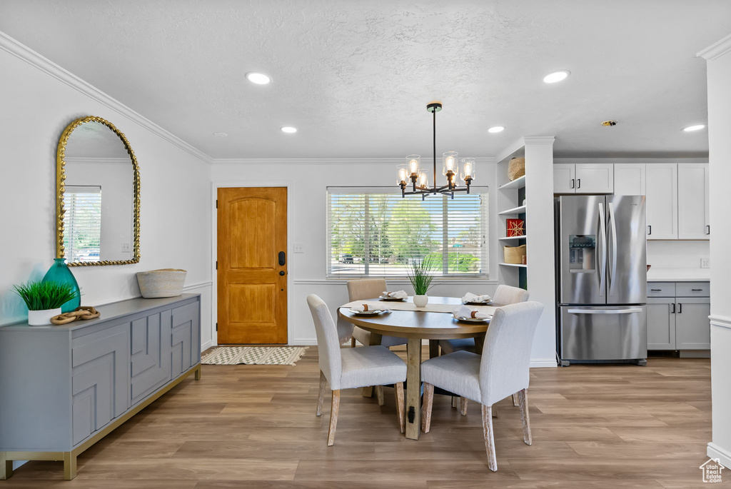 Dining area featuring light wood finished floors, plenty of natural light, recessed lighting, a chandelier, and ornamental molding