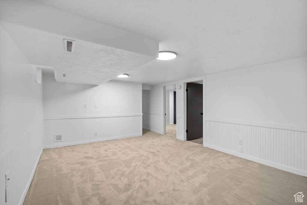 Finished below grade area featuring carpet, wainscoting, and a textured ceiling