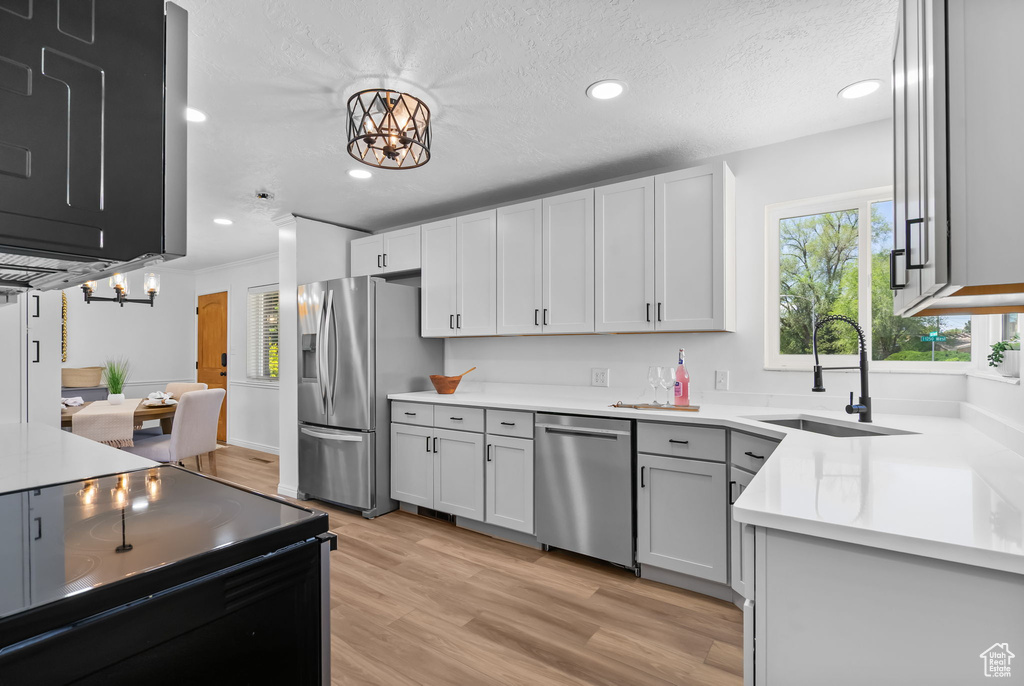 Kitchen featuring appliances with stainless steel finishes, a sink, a chandelier, recessed lighting, and light wood-type flooring