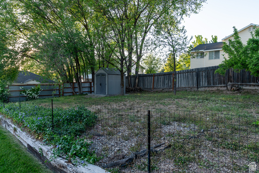 Fenced backyard featuring a shed and an outdoor structure