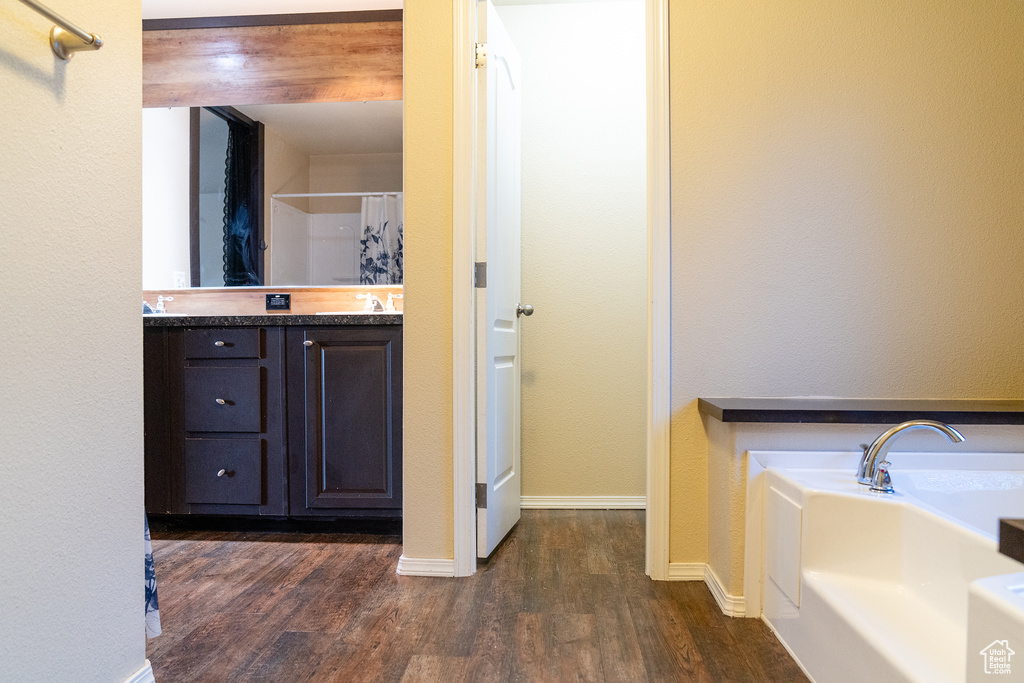 Full bathroom featuring wood finished floors, a shower with curtain, vanity, a bathtub, and baseboards
