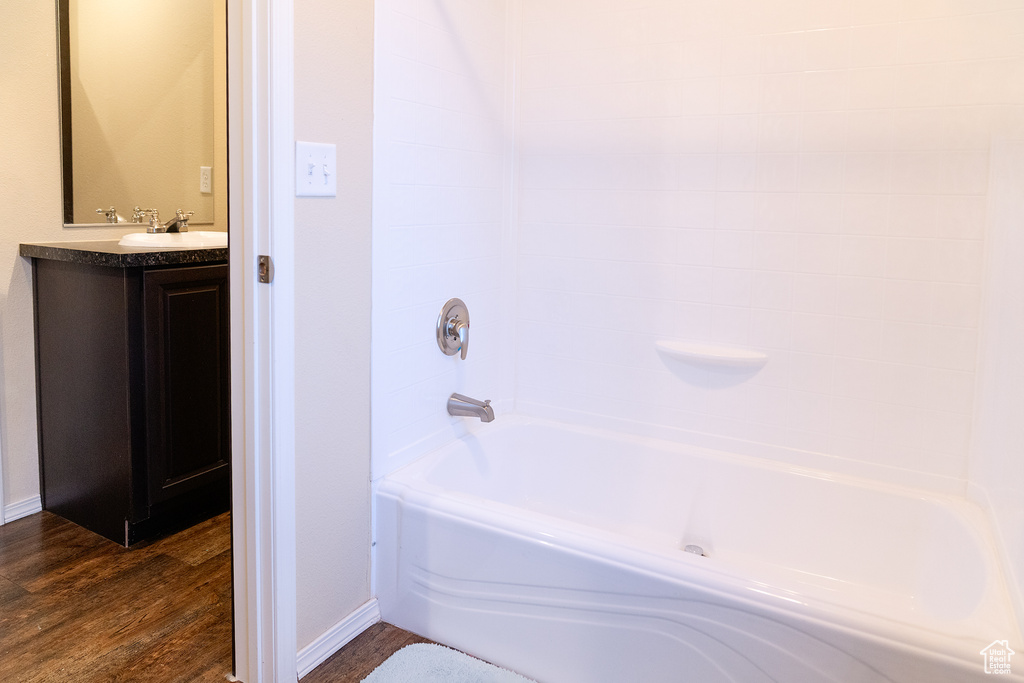 Full bathroom featuring wood finished floors, baseboards, vanity, and tub / shower combination