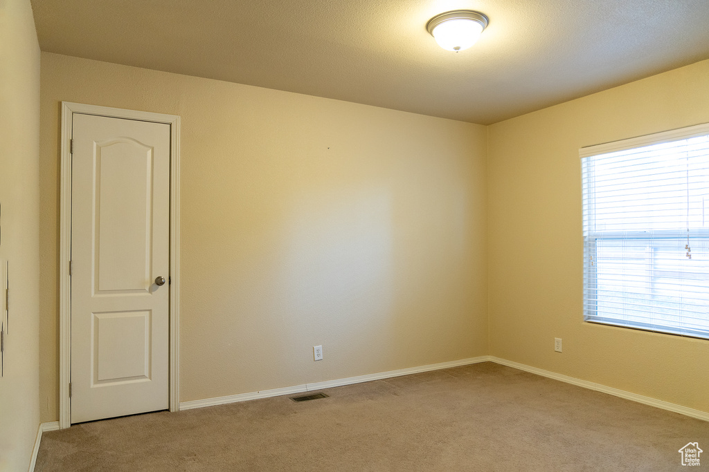 Empty room featuring light carpet and baseboards