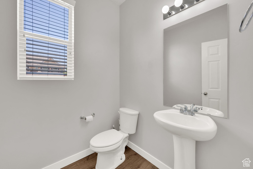 Bathroom featuring baseboards, wood finished floors, and toilet