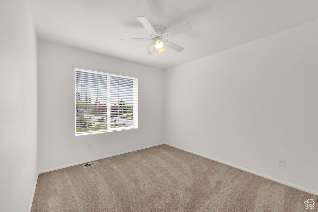 Carpeted empty room with a ceiling fan and baseboards