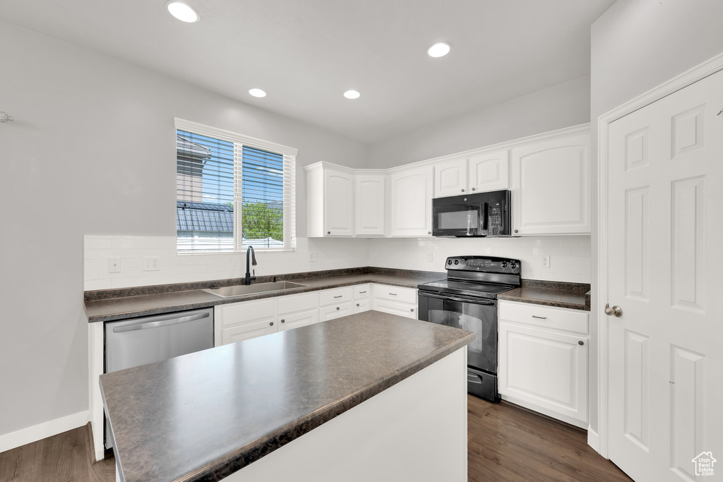Kitchen with black appliances, a sink, dark countertops, white cabinets, and recessed lighting