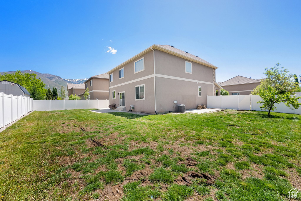 Rear view of house with a patio area, stucco siding, and central AC unit