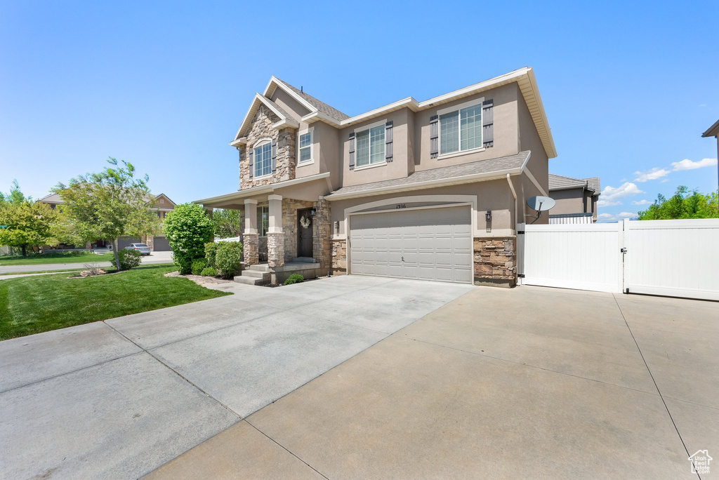Craftsman house featuring stone siding, a gate, stucco siding, an attached garage, and concrete driveway