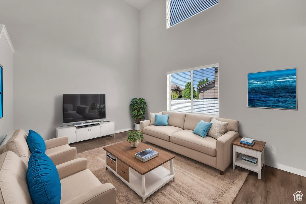 Living room featuring a high ceiling, wood finished floors, and baseboards