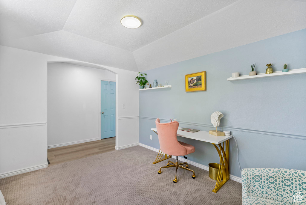 Home office featuring carpet, lofted ceiling, and baseboards