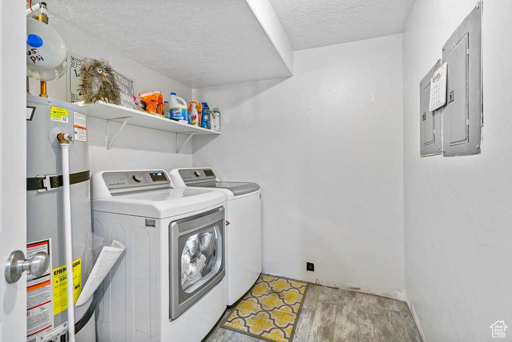 Laundry area with water heater, separate washer and dryer, a textured ceiling, and electric panel