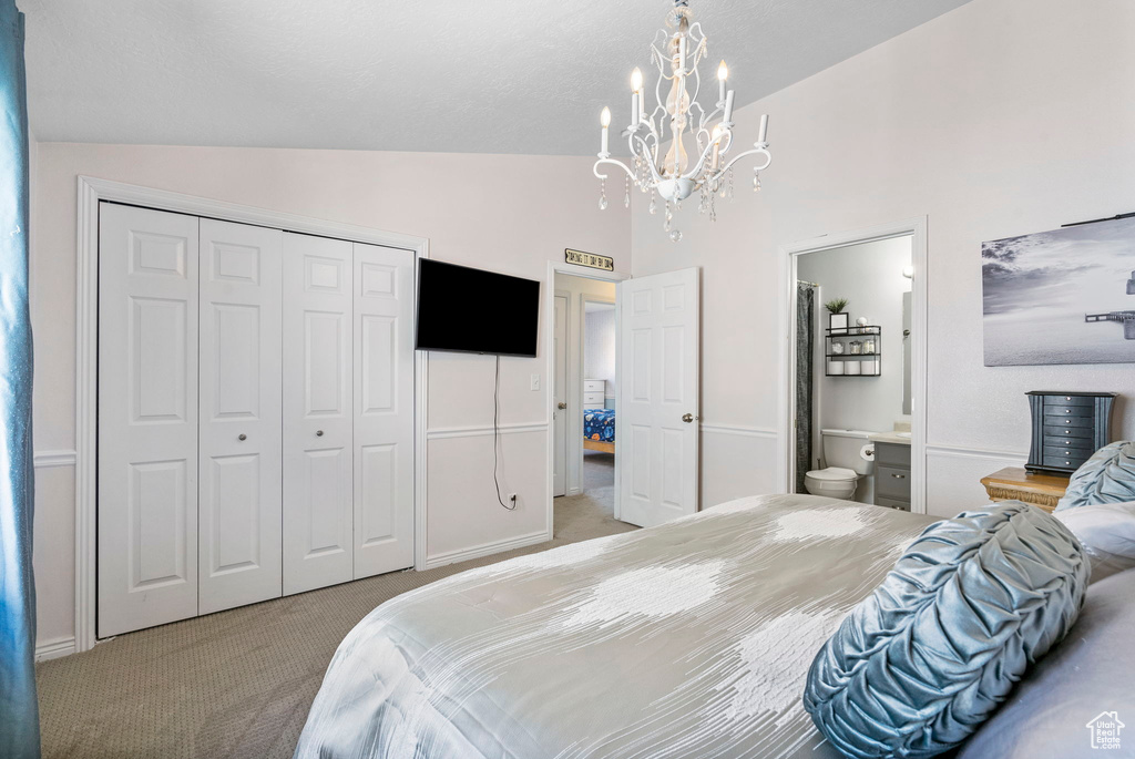Carpeted bedroom with a chandelier, a closet, high vaulted ceiling, ensuite bath, and baseboards