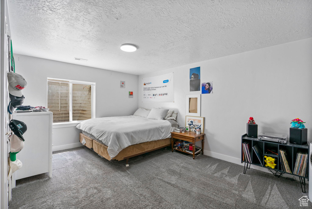 Carpeted bedroom featuring a textured ceiling and baseboards