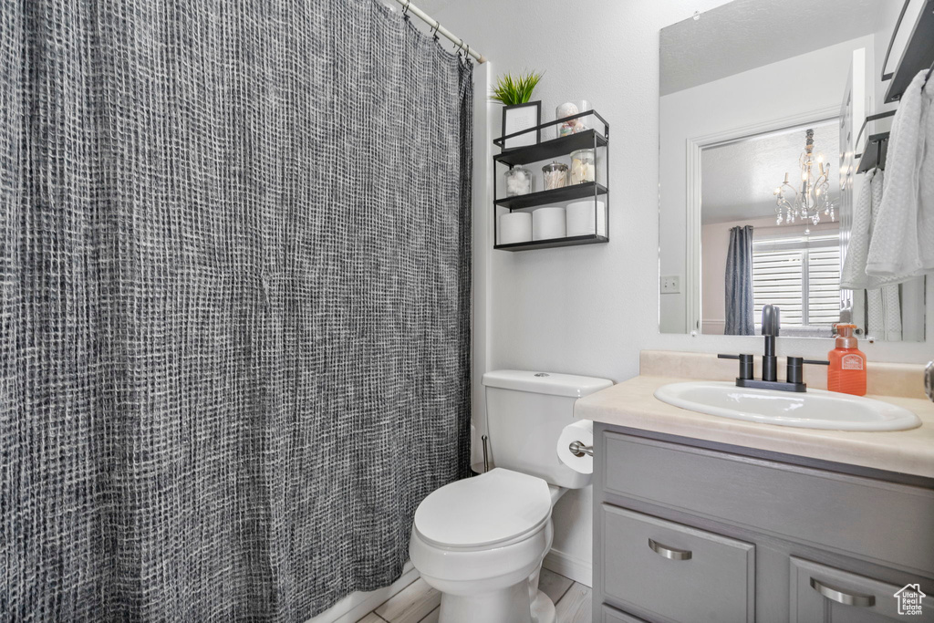 Full bathroom with vanity, toilet, a chandelier, and curtained shower