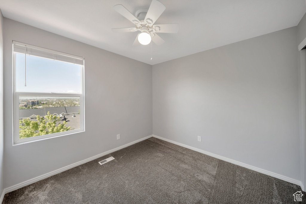 Empty room with carpet floors, baseboards, and a ceiling fan