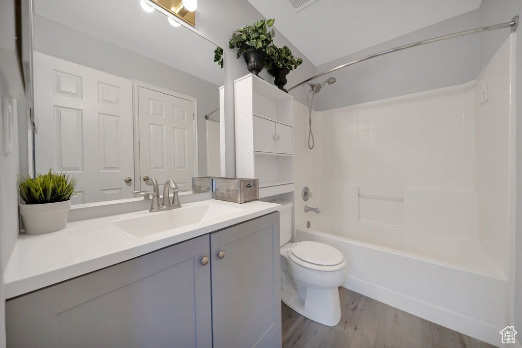 Bathroom featuring vanity, toilet, wood finished floors, and tub / shower combination