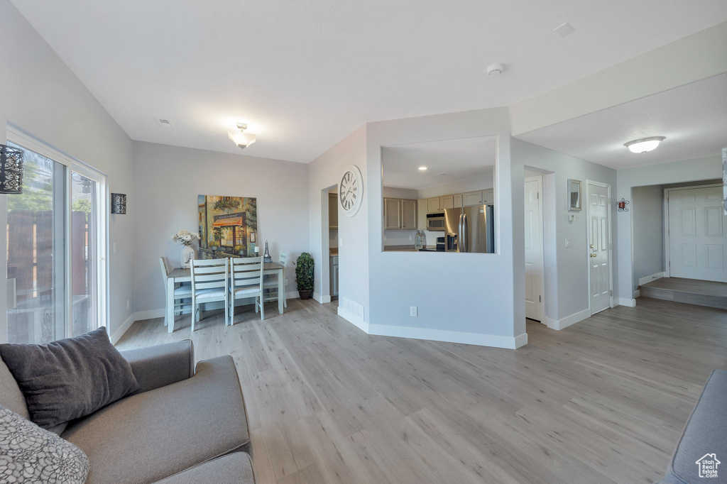 Living room with light wood finished floors, baseboards, and recessed lighting