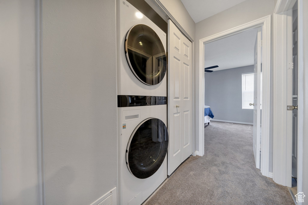 Washroom with stacked washer / dryer, carpet floors, and baseboards