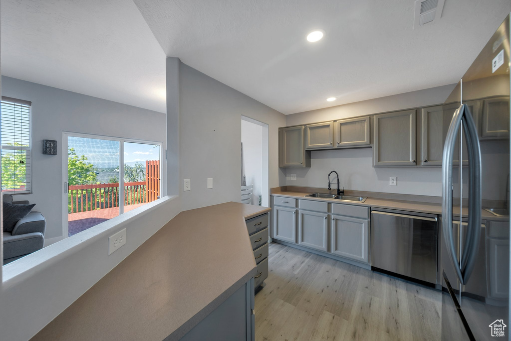 Kitchen featuring a sink, stainless steel appliances, light wood finished floors, recessed lighting, and gray cabinets