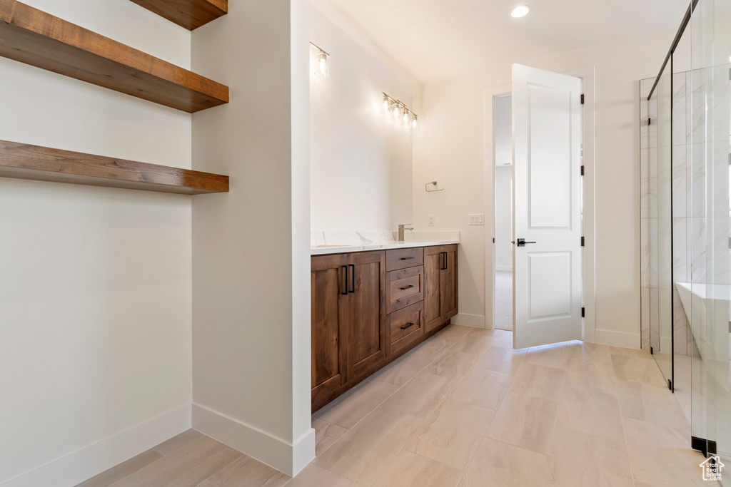 Full bathroom featuring a shower stall, double vanity, baseboards, and recessed lighting