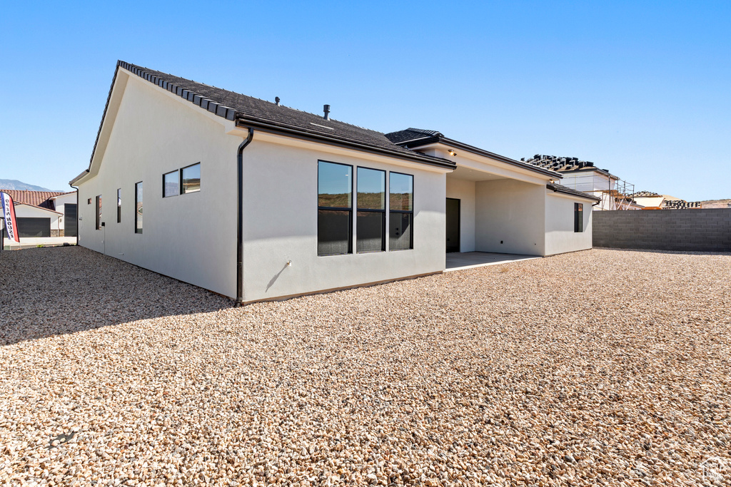 Rear view of house with fence, stucco siding, and a patio