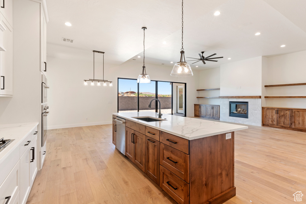 Kitchen with a sink, ceiling fan, recessed lighting, brown cabinets, and light wood-style floors